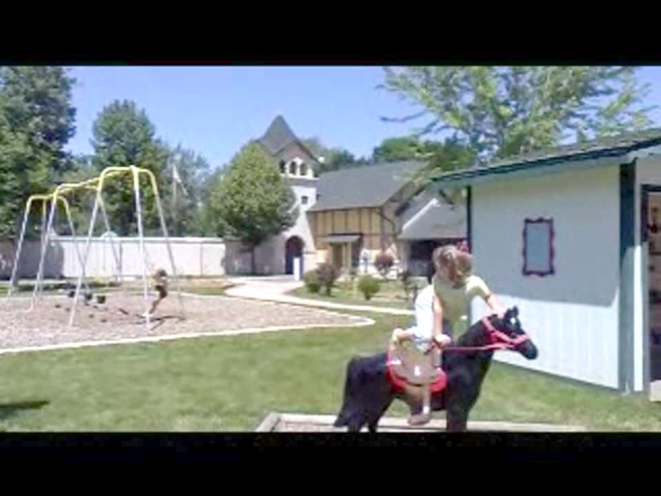 Video thumbnail showing: A girl swings outdoors while her older sisters play on a fake horse that they wouldn't let her play on. Their dad holds up a tot boy and says he's going to have him ride the horse \